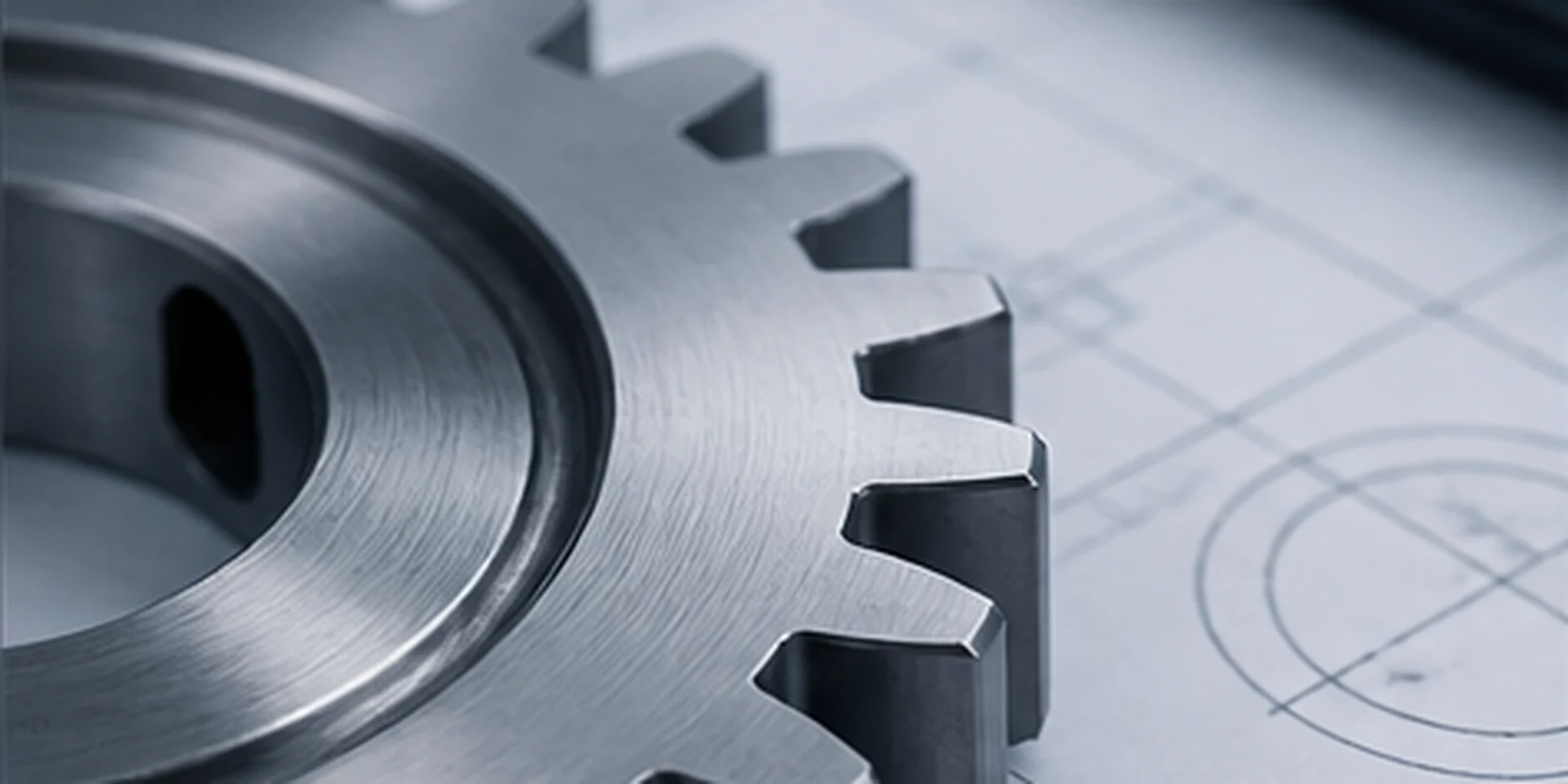 Machined steel gear resting on a technical drawing
